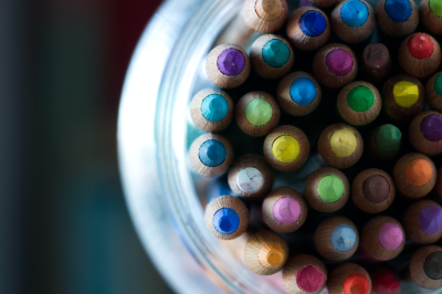 A jar filled with many different coloured pencils